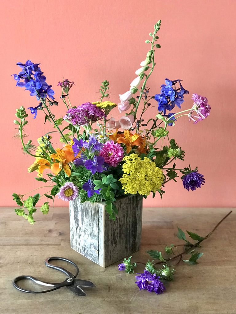 small wood box with colorful summer flowers arranged in a wildflower style